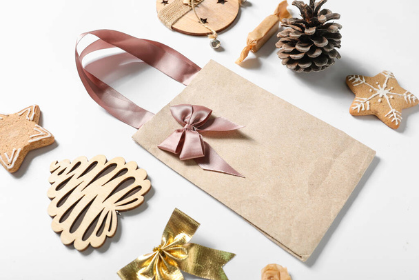 Composition with paper bag, Christmas decorations and sweets on white background, closeup - Fotografie, Obrázek