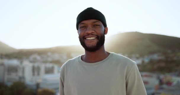 Face, happy and street style with a black man outdoor in the city with nature in the background during summer. Portrait, fashion and urban with a handsome young male standing outside in a bright town. - Footage, Video