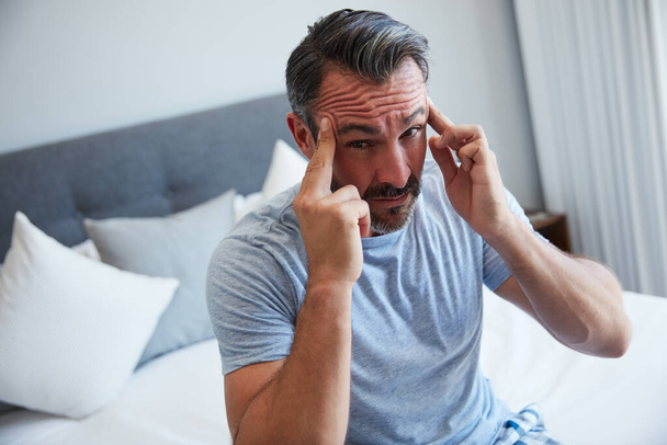 This is the worst way to start a day ever. an attractive mature man suffering from a headache in his bedroom in the morning - Fotoğraf, Görsel