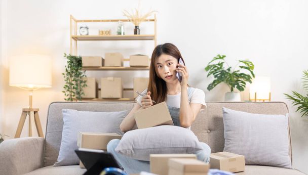 E-commerce businessman is talking on the phone with a customer who comes in to inquire and place her order, Woman writes mailbox address in preparation for delivery, SME entrepreneur, Packing box. - Photo, Image