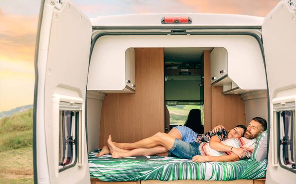 Молодая пара спит обнявшись в кровати своего фургона с переплетающимися ногами - Фото, изображение