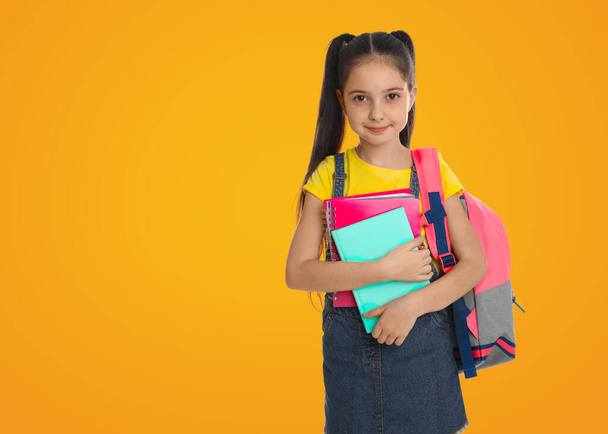 Little girl with school stationery on yellow background, space for text - Foto, immagini