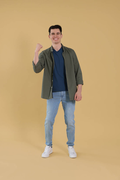 Full length portrait of happy young man on beige background - Фото, зображення