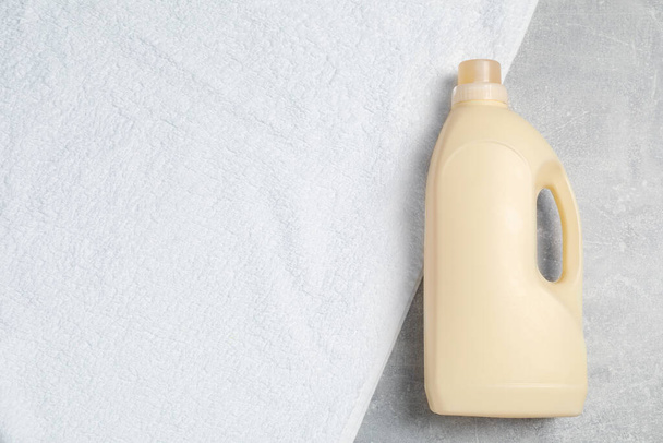 Bottle of laundry detergent and clean towel on light grey table, top view. Space for text - Fotografie, Obrázek