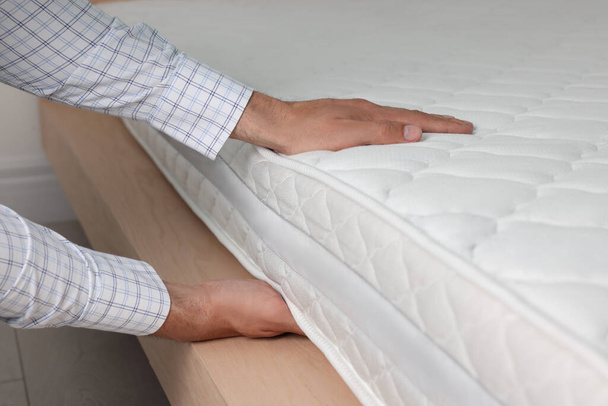Man touching soft white mattress indoors, closeup - Foto, Imagem