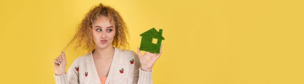Feliz comprador de casa. Una joven tiene en sus manos un modelo de casa verde. El concepto de energía verde, ecología. - Foto, imagen