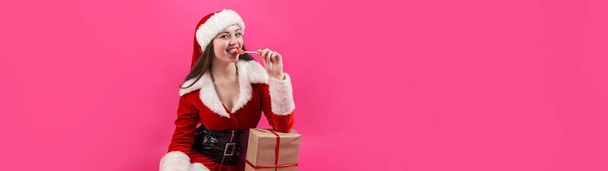 Beautiful young woman in Santa Claus costume against the red background. - Foto, imagen