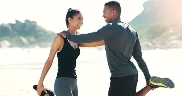 Trainingseinheiten funktionieren mit bae besser. ein glückliches junges Paar dehnt sich beim Sport am Strand - Foto, Bild