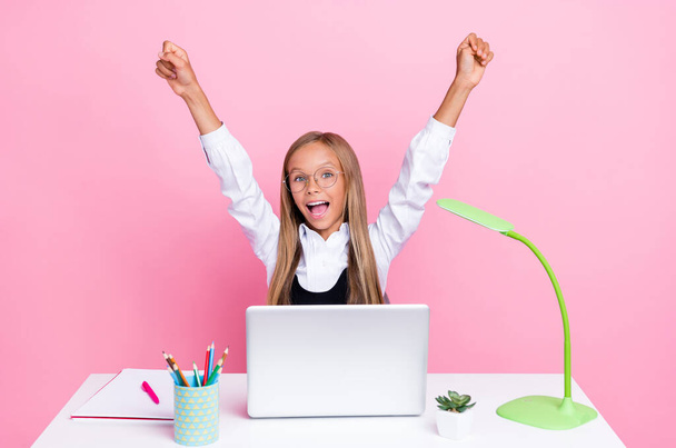 Photo of young beautiful schoolkid girl blonde hair eyeglasses excited fists up celebrate her homework laptop online isolated on pink color background. - Fotoğraf, Görsel