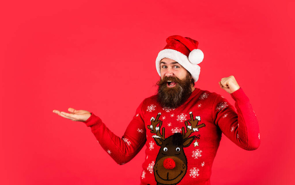 Promoting goods. Winter holiday fun. Hipster with mustache winter sweater. Stunning and Unique. Lifestyle you deserve. New year party. Christmas time. Product presentation. Bearded man santa hat. - Photo, image