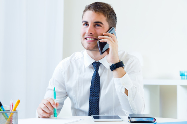 Young handsome man working in his office with mobile phone. - Photo, image