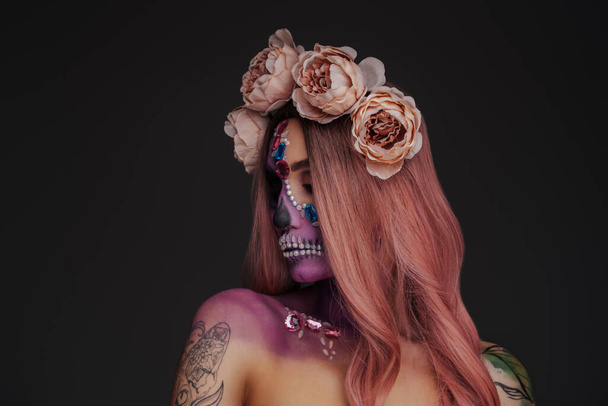 Colpo di bellezza femminile con tatuaggi e ghirlanda di rose sullo sfondo scuro. - Foto, immagini