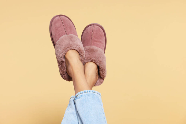 Woman in warm soft slippers on beige background, closeup. Space for text - Photo, Image