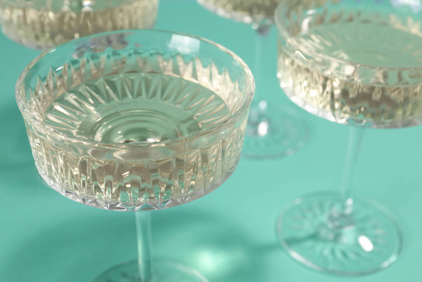 Glasses of expensive white wine on turquoise background, closeup - Фото, зображення
