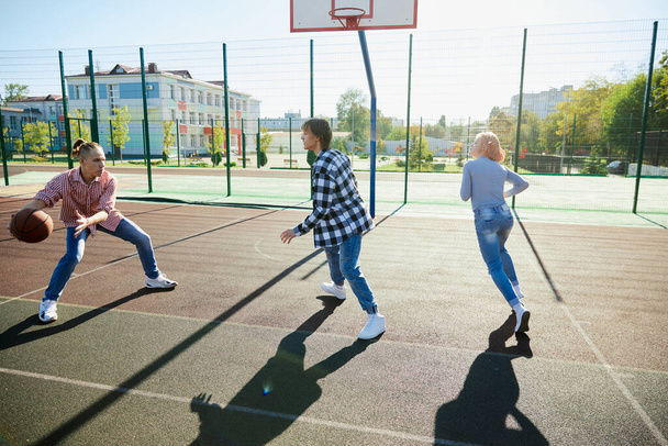 Leisure games. Group of friends bonding outdoors to play street basketball. Teens wearing casual style clothes. Look happy, delighted. Social gathering, friendship, team and happy childhood - Φωτογραφία, εικόνα