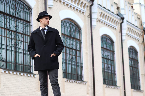 Men's photo shoot in a classic plaid suit and a hat against the backdrop of an old building. - Photo, Image