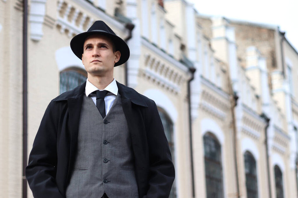 Фотосесія чоловіків у класичному костюмі та капелюсі на тлі старої будівлі
. - Фото, зображення