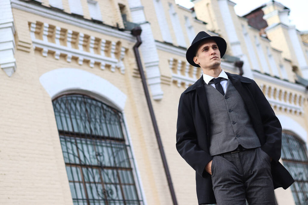 Мужская фотосессия в классическом клетчатом костюме и шляпе на фоне старого здания. - Фото, изображение
