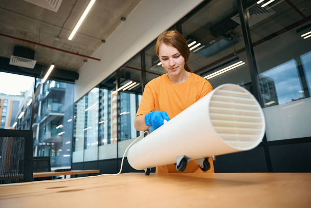 Kobieta instaluje generator ozonu na biurku, aby oczyścić powietrze w obszarze współpracowników. - Zdjęcie, obraz