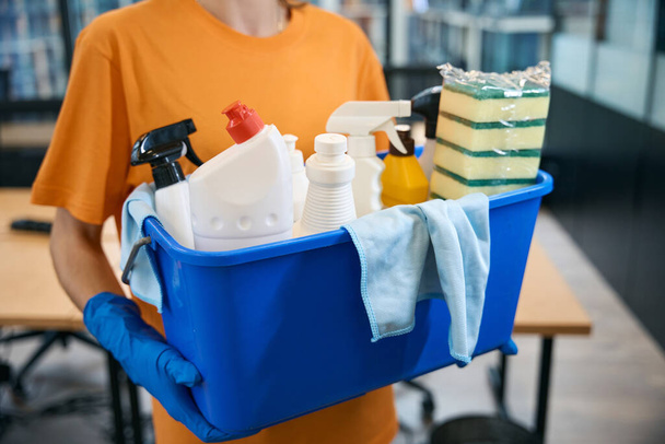 Cleaner cleaning company holds in her hands professional set of gadgets for cleaning and disinfection - bucket, sponges, spray, napkins, detergents - Foto, Imagem