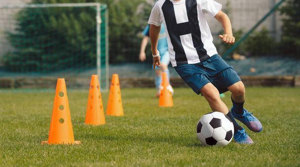 Garçon Dribble un ballon de football entre les cônes. Cours d'entraînement de football pour enfants. Les enfants au camp d'été sportif  - Photo, image