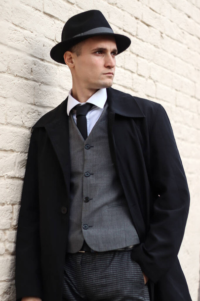 Men's photo shoot in a classic plaid suit and hat against a brick wall. - Fotó, kép