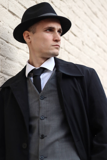 Séance photo pour hommes en costume à carreaux classique et chapeau contre un mur de briques. - Photo, image