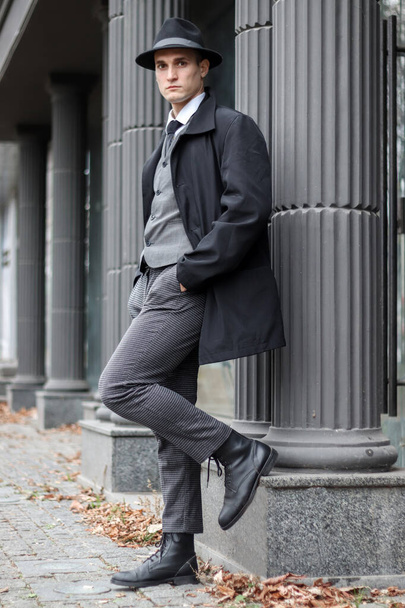 Männerfotosession im klassisch karierten Anzug und Hut vor dem Hintergrund von Säulen. - Foto, Bild