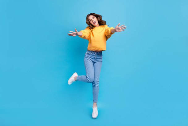 Full length photo of funny dreamy lady wear yellow sweater jumping high ready hug you isolated blue color background. - Foto, immagini