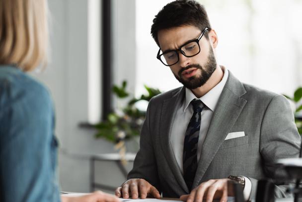 Businessman in eyeglasses talking to blurred job seeker in office  - Foto, Imagen