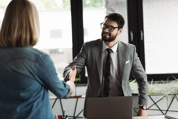 Empresário apertando a mão de candidato a emprego desfocado durante entrevista no escritório  - Foto, Imagem
