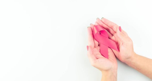 Świadomość raka. Symbol opieki zdrowotnej różowa wstążka w rękach kobiety na białym tle. Pomysł na podparcie piersi. Światowy Dzień Raka - Zdjęcie, obraz