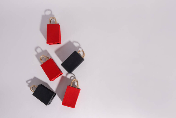 Креативная концепция дизайна мероприятия "Черная пятница", красные и черные сумки для покупок с тенями на заднем плане, пространство для копирования - Фото, изображение