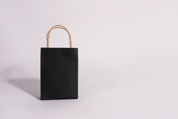 Μαύρη τσάντα αγορών, μικρή χάρτινη σακούλα σε λευκό φόντο, αντίγραφο χώρου, μαύρη Παρασκευή έννοια - Φωτογραφία, εικόνα