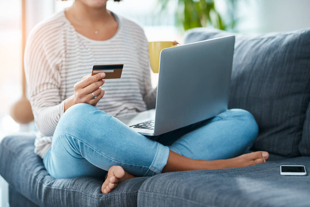 Online shopping on a cool saturday Why not. an unrecognizable young woman using her laptop and credit card in her living room - Fotografie, Obrázek