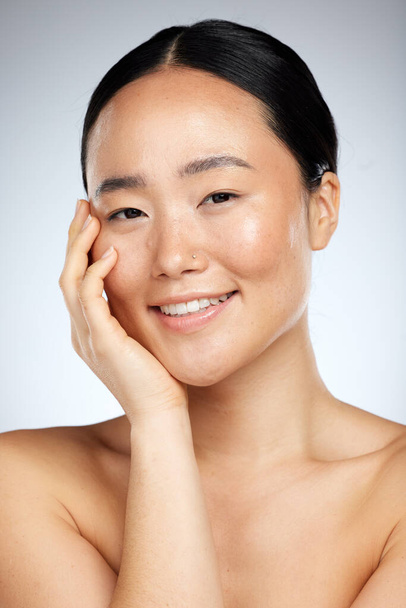 Beauty, skincare and face of woman in studio for facial, grooming and cleaning against a grey background. Portrait, face and asian wellness model smile, relax and happy with cosmetics and dermatology. - Fotó, kép
