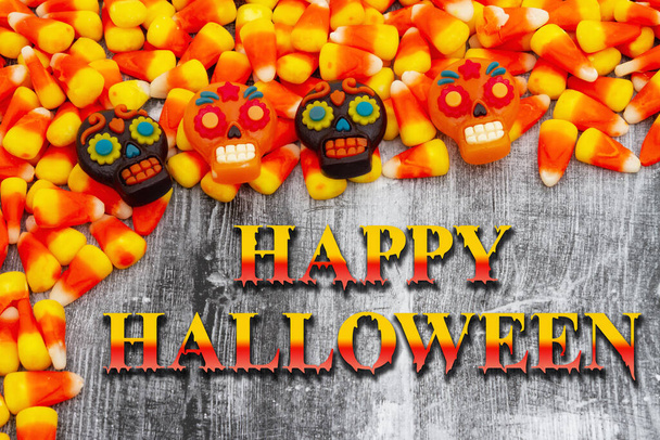 Feliz Halloween saludo con naranja y amarillo caramelo maíz y calaveras - Foto, imagen