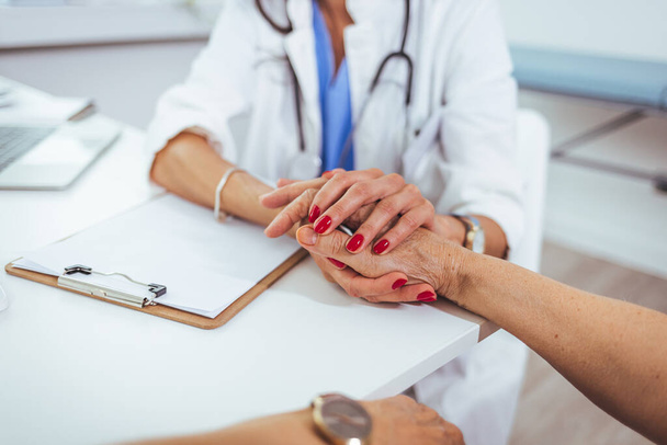 Female doctor holding hands of female patient at meeting as women health medical care concept express trust support empathy about miscarriage, help hope in cancer disease therapy, close up view - Foto, Bild