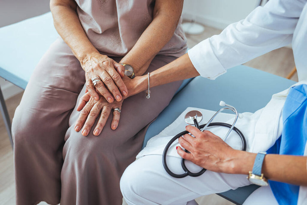 Health worker holding patient's hand. Cropped shot of a senior woman holding hands with a nurse. Doctor holding touching hands senior or elderly old lady woman patient with love, care, helping. - Фото, зображення