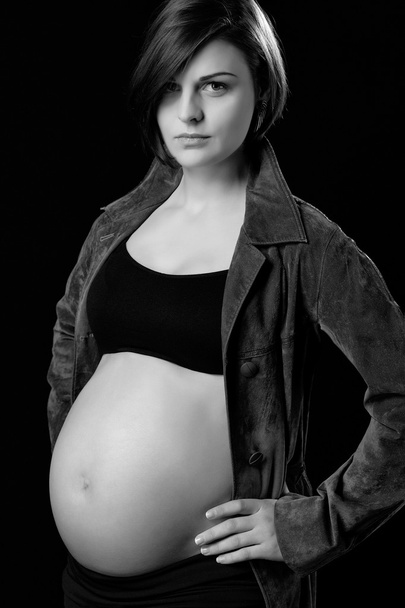 Attractive young pregnant woman with naked belly on black background - Fotoğraf, Görsel