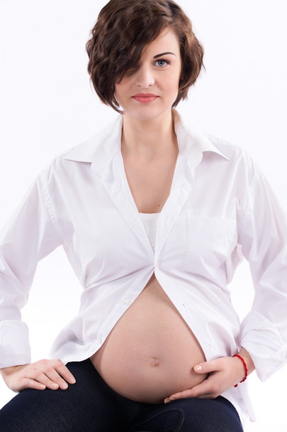 Attractive young pregnant woman with naked belly on white background - Foto, Imagen