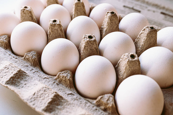 huevos de granja naturales en bandeja de cartón. Vista lateral, enfoque suave. Huevos apilados en fila en bandeja reutilizable hecha de papel reciclado. concepto de alimentación saludable - Foto, imagen