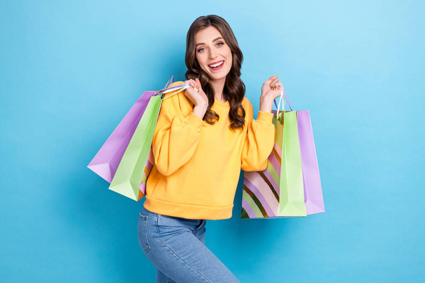 Photo portrait of attractive young girl carry shopping bags enjoy weekend dressed stylish yellow outfit isolated on blue color background. - Fotografie, Obrázek