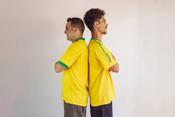 Black Brothers With Yellow Brazilian Shirt and Flag Cheering Isolates on White (en inglés). Aficionados al fútbol animando a Brasil para ser el campeón. - Foto, Imagen