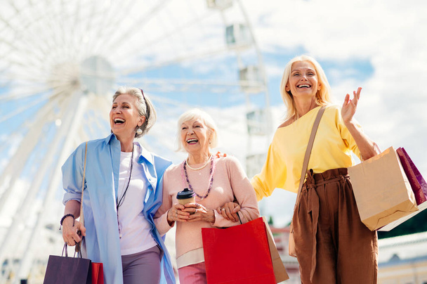 Beautiful happy senior women meeting outdoors and shopping in the city centre - Pretty and joyful old female adult people bonding and having fun outdoors - 写真・画像