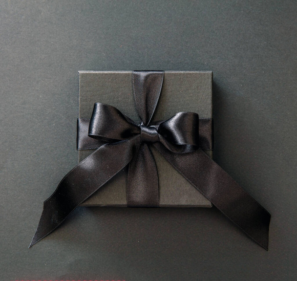 Black Friday Sale. Gift box with black ribbon isolated on black, top view, Christmas presents concept. - Photo, Image