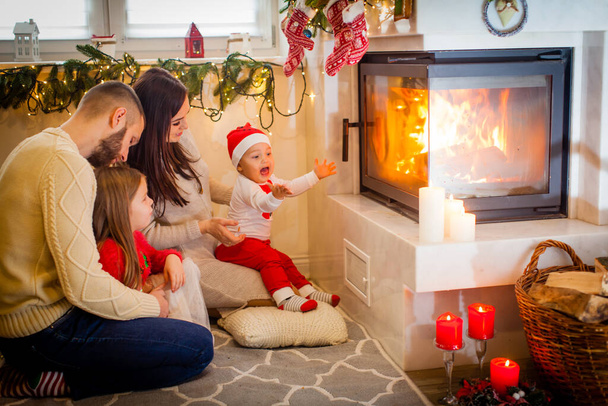 Happy family - parents and children sitting by fireplace on Christmas Eve - Foto, immagini