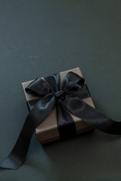 Gift box with black ribbon isolated on black, copy space. Black Friday Sale and Christmas presents - Fotografie, Obrázek