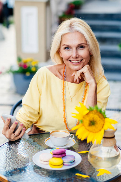 Beautiful and happy senior adult woman sitting at the bar cafeteria - Stylish fashionable old mature people relaxing in a modern cafe outdoors - Foto, Imagen
