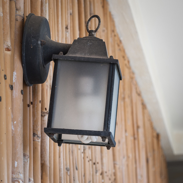 Уличная лампа в старом стиле на бамбуковой стене
 - Фото, изображение